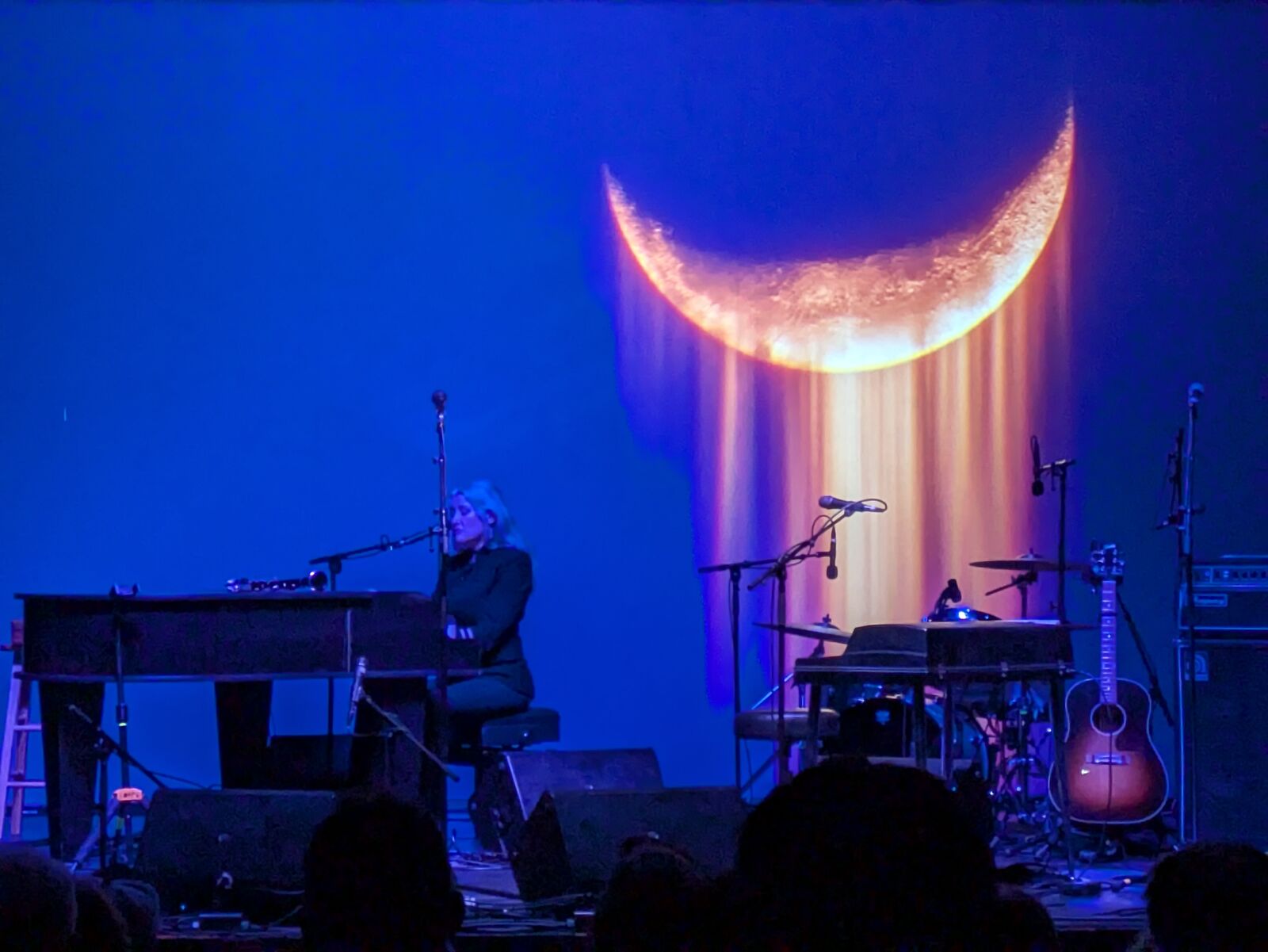 Concert stage lit with a glowing crescent moon backdrop